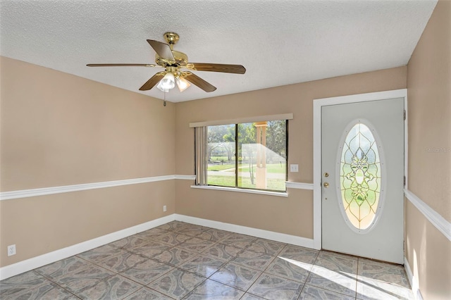 foyer featuring tile patterned flooring, a ceiling fan, baseboards, and a textured ceiling