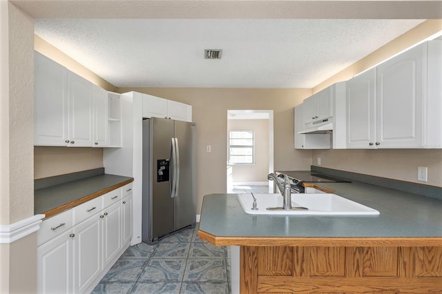 kitchen featuring dark countertops, under cabinet range hood, stainless steel refrigerator with ice dispenser, white cabinets, and a sink