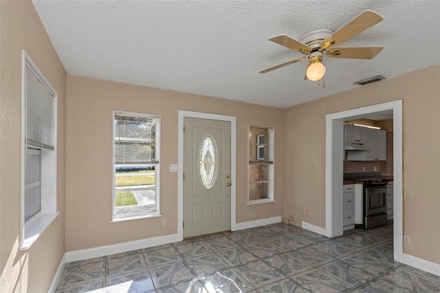 foyer with visible vents, a textured ceiling, baseboards, and a ceiling fan