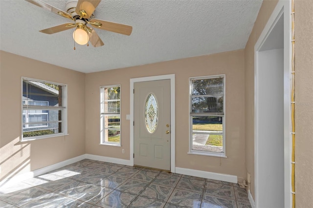 entrance foyer featuring a textured ceiling, a ceiling fan, and baseboards