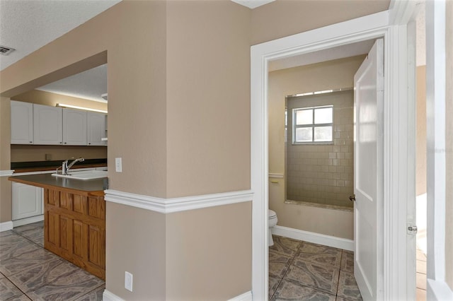 full bath featuring vanity, toilet, visible vents, and baseboards