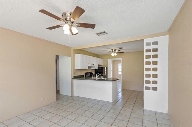 kitchen featuring under cabinet range hood, dark countertops, white cabinets, light tile patterned floors, and ceiling fan