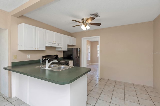 kitchen with visible vents, freestanding refrigerator, a sink, under cabinet range hood, and dark countertops