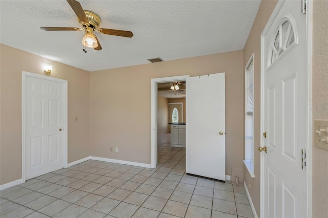 unfurnished room featuring light tile patterned floors, baseboards, a textured ceiling, and a ceiling fan