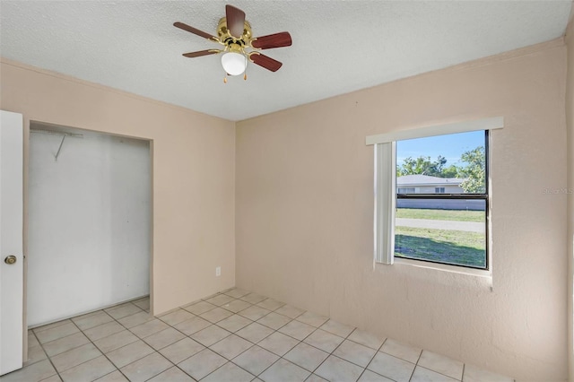 spare room featuring light tile patterned floors, a textured ceiling, and a ceiling fan