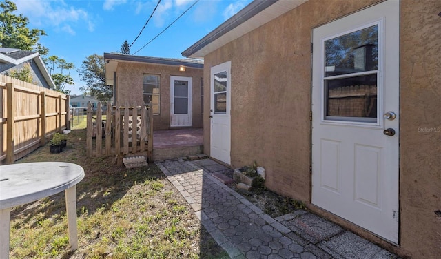 entrance to property featuring fence and stucco siding