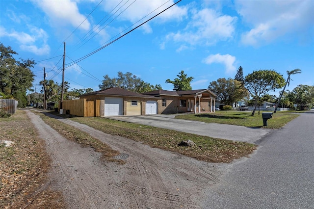 view of front of property featuring a front lawn, dirt driveway, and fence