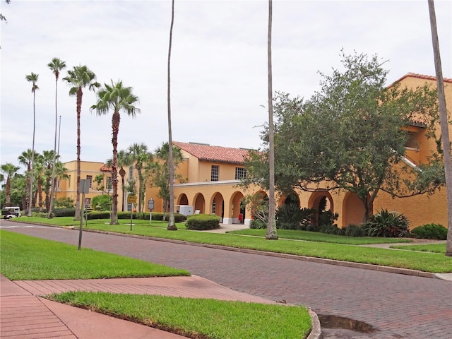 view of front of property with a front yard, a tile roof, and stucco siding