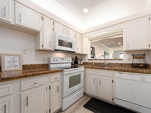 kitchen with dark stone countertops, white appliances, recessed lighting, a sink, and light wood-style floors