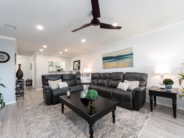 living area featuring ceiling fan, visible vents, a textured ceiling, and light wood-style flooring