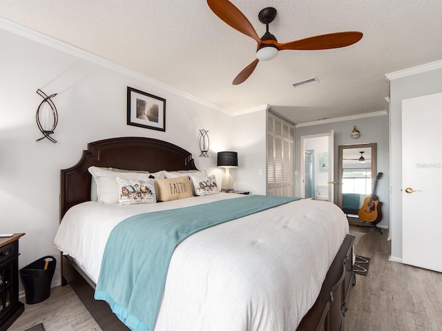 bedroom featuring visible vents, wood finished floors, and crown molding