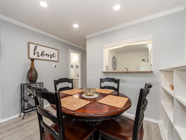 dining room featuring baseboards, crown molding, and light wood finished floors