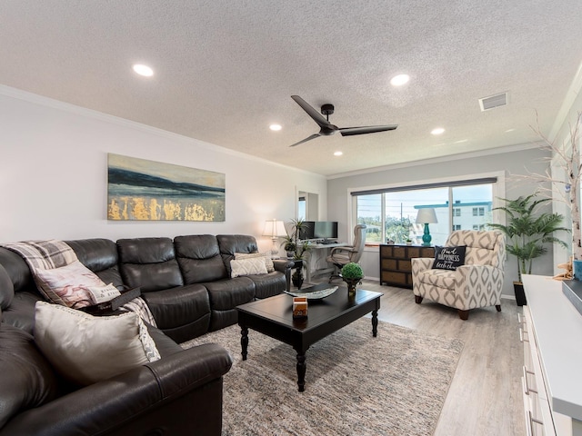 living area featuring light wood-type flooring, visible vents, a textured ceiling, and crown molding