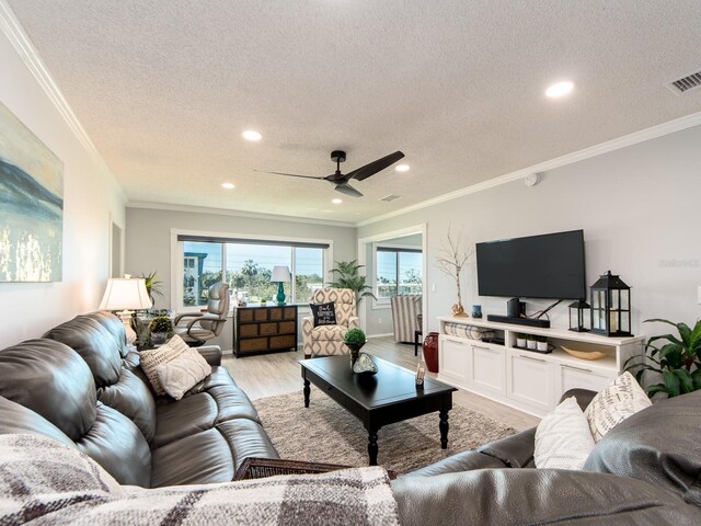 living room featuring visible vents, ceiling fan, light wood-style floors, and ornamental molding