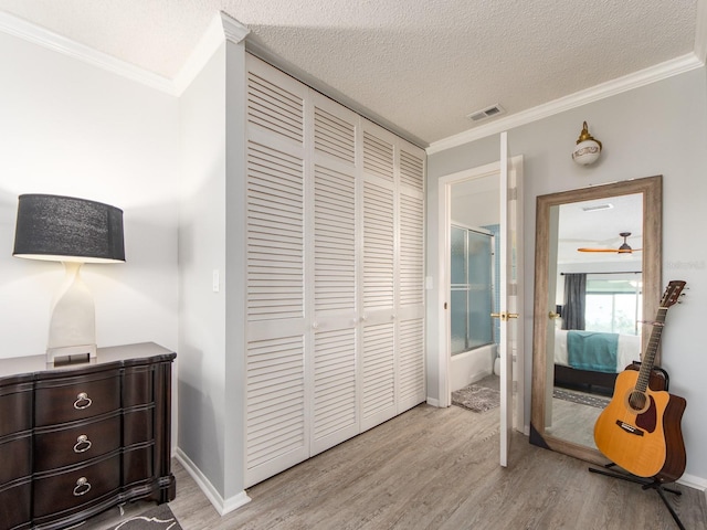 bedroom with visible vents, crown molding, wood finished floors, a closet, and a textured ceiling