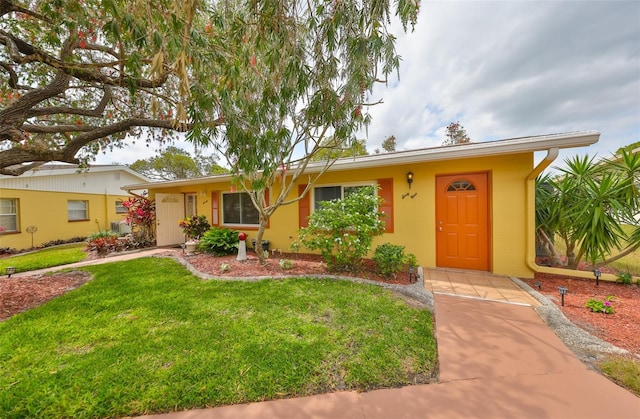 ranch-style home with concrete block siding and a front lawn