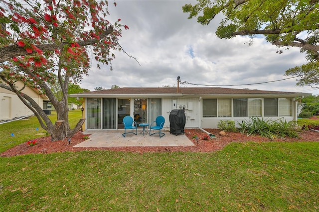 rear view of property featuring a patio, a lawn, and a sunroom