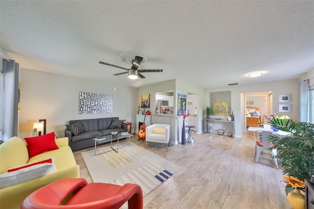 living area with ceiling fan, a textured ceiling, and wood finished floors