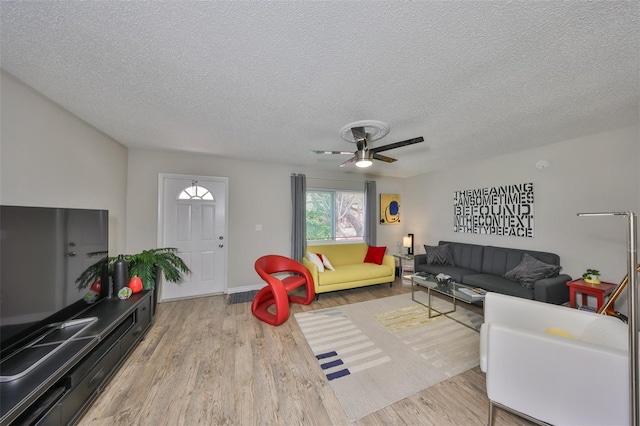 living area featuring wood finished floors, a textured ceiling, and ceiling fan