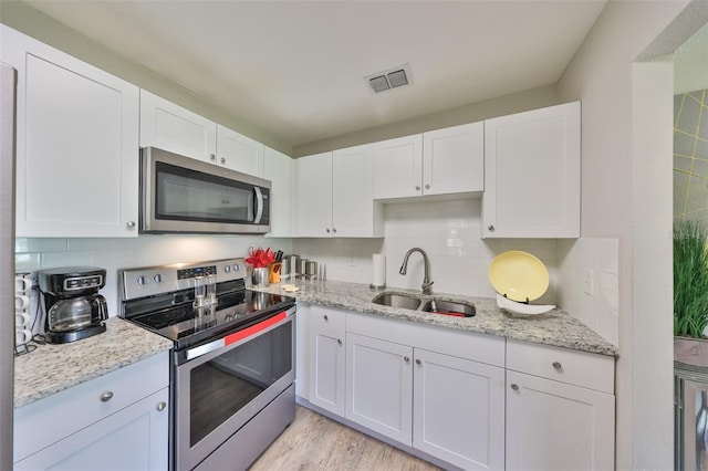 kitchen featuring visible vents, white cabinets, stainless steel appliances, and a sink