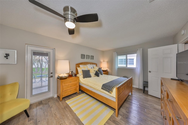 bedroom featuring a ceiling fan, access to outside, wood finished floors, and a textured ceiling