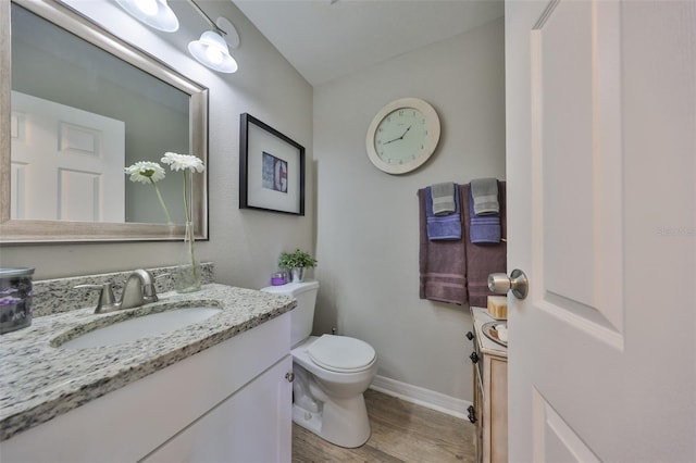 bathroom featuring vanity, toilet, wood finished floors, and baseboards