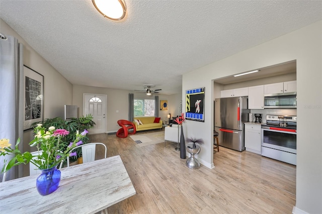 kitchen with white cabinets, a textured ceiling, stainless steel appliances, and light wood-type flooring