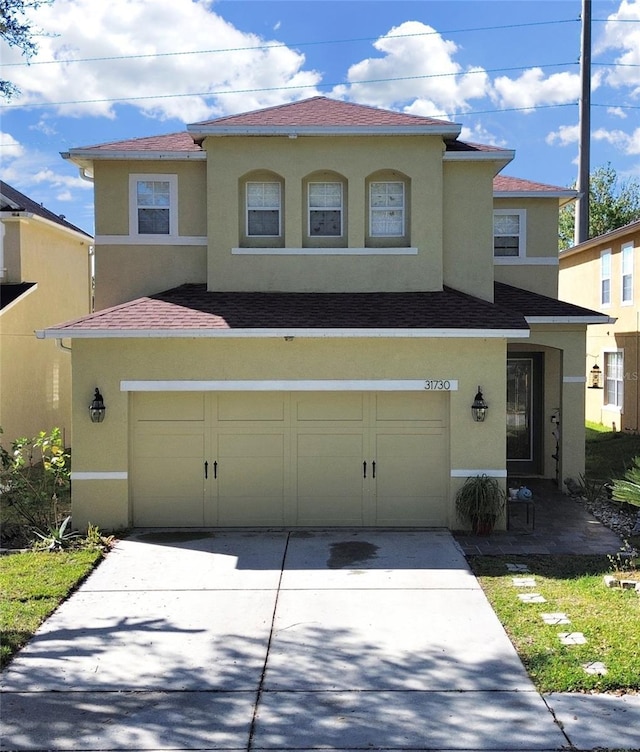 mediterranean / spanish-style house with stucco siding, concrete driveway, an attached garage, and a shingled roof