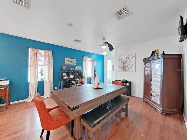 dining space with light wood-type flooring, visible vents, and a ceiling fan