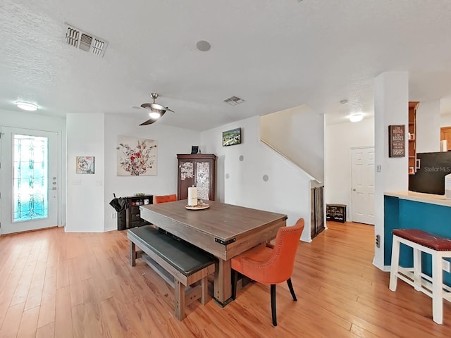 dining space featuring visible vents, a textured ceiling, and light wood-style flooring