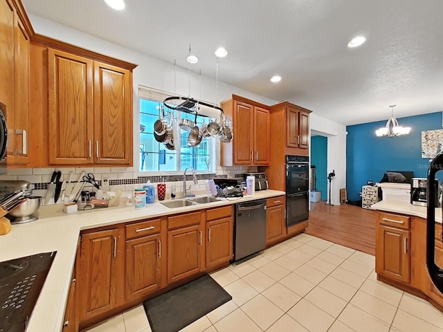 kitchen with decorative backsplash, black appliances, light countertops, and a sink