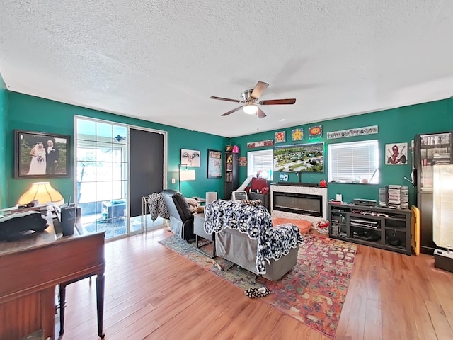 living room with plenty of natural light, a textured ceiling, a ceiling fan, and wood finished floors