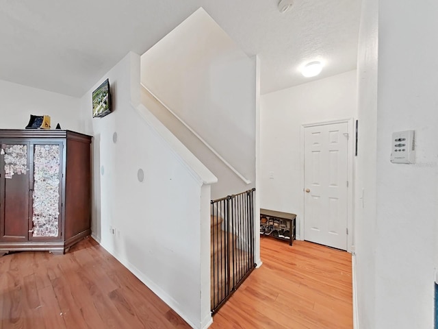 corridor with an upstairs landing and light wood finished floors