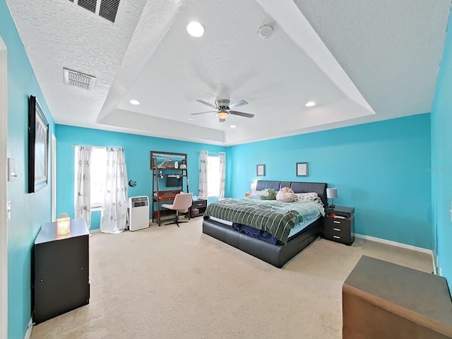 bedroom with a tray ceiling, a textured ceiling, visible vents, and carpet flooring