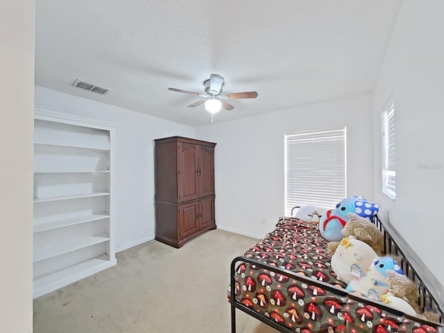 bedroom with a ceiling fan, baseboards, visible vents, and light carpet