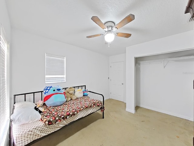 bedroom featuring light carpet, a ceiling fan, a textured ceiling, a closet, and baseboards