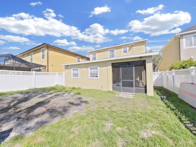 rear view of property with a fenced backyard, a lawn, a sunroom, and stucco siding