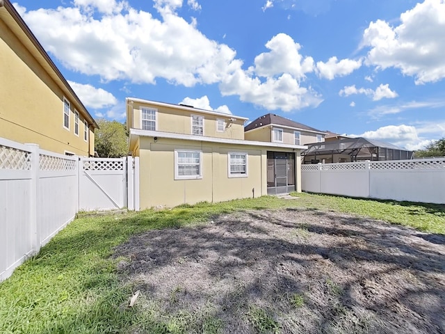 rear view of property with a gate, a fenced backyard, a sunroom, stucco siding, and a lawn