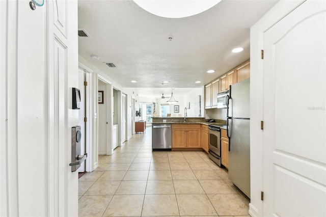 kitchen with dark countertops, visible vents, light tile patterned floors, a peninsula, and stainless steel appliances