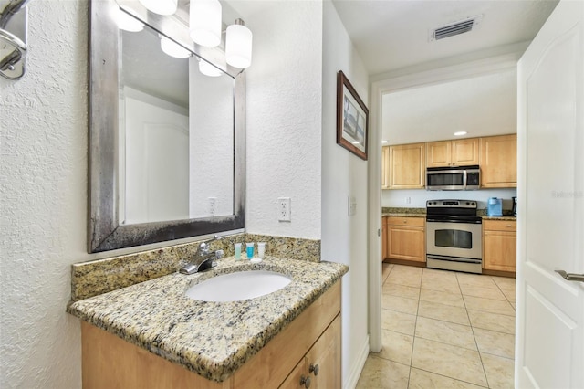 bathroom featuring tile patterned floors, visible vents, vanity, and a textured wall