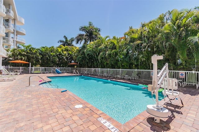 community pool with a patio area and fence