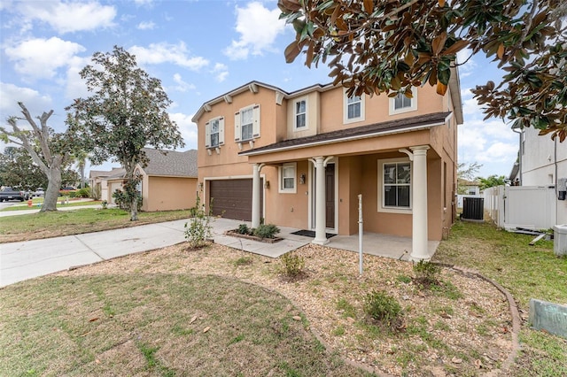 traditional-style home featuring an attached garage, fence, stucco siding, cooling unit, and driveway