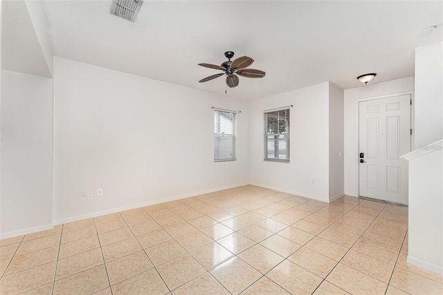 empty room featuring light tile patterned floors, baseboards, visible vents, and ceiling fan