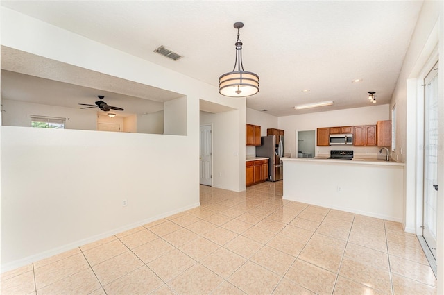 kitchen with brown cabinetry, visible vents, stainless steel appliances, light countertops, and open floor plan