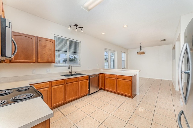 kitchen with light countertops, light tile patterned floors, appliances with stainless steel finishes, a peninsula, and a sink