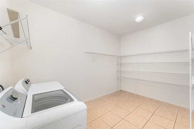 clothes washing area with light tile patterned floors, laundry area, baseboards, and separate washer and dryer