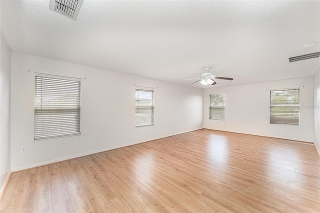 unfurnished room with light wood-type flooring, visible vents, and a ceiling fan