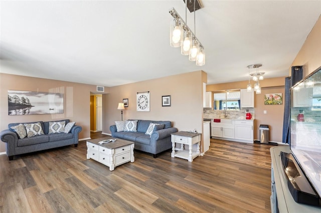 1021 Augusta Dr, Sun City Center, FL 33573 - living area featuring a notable chandelier, visible vents, dark wood-style flooring, and baseboards