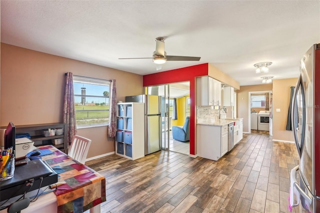 1021 Augusta Dr, Sun City Center, FL 33573 - kitchen with wood finished floors, white cabinetry, stainless steel appliances, and separate washer and dryer