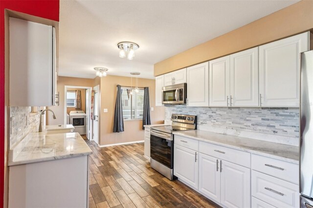 1021 Augusta Dr, Sun City Center, FL 33573 - kitchen featuring a sink, washer / clothes dryer, dark wood-style floors, white cabinetry, and stainless steel appliances
